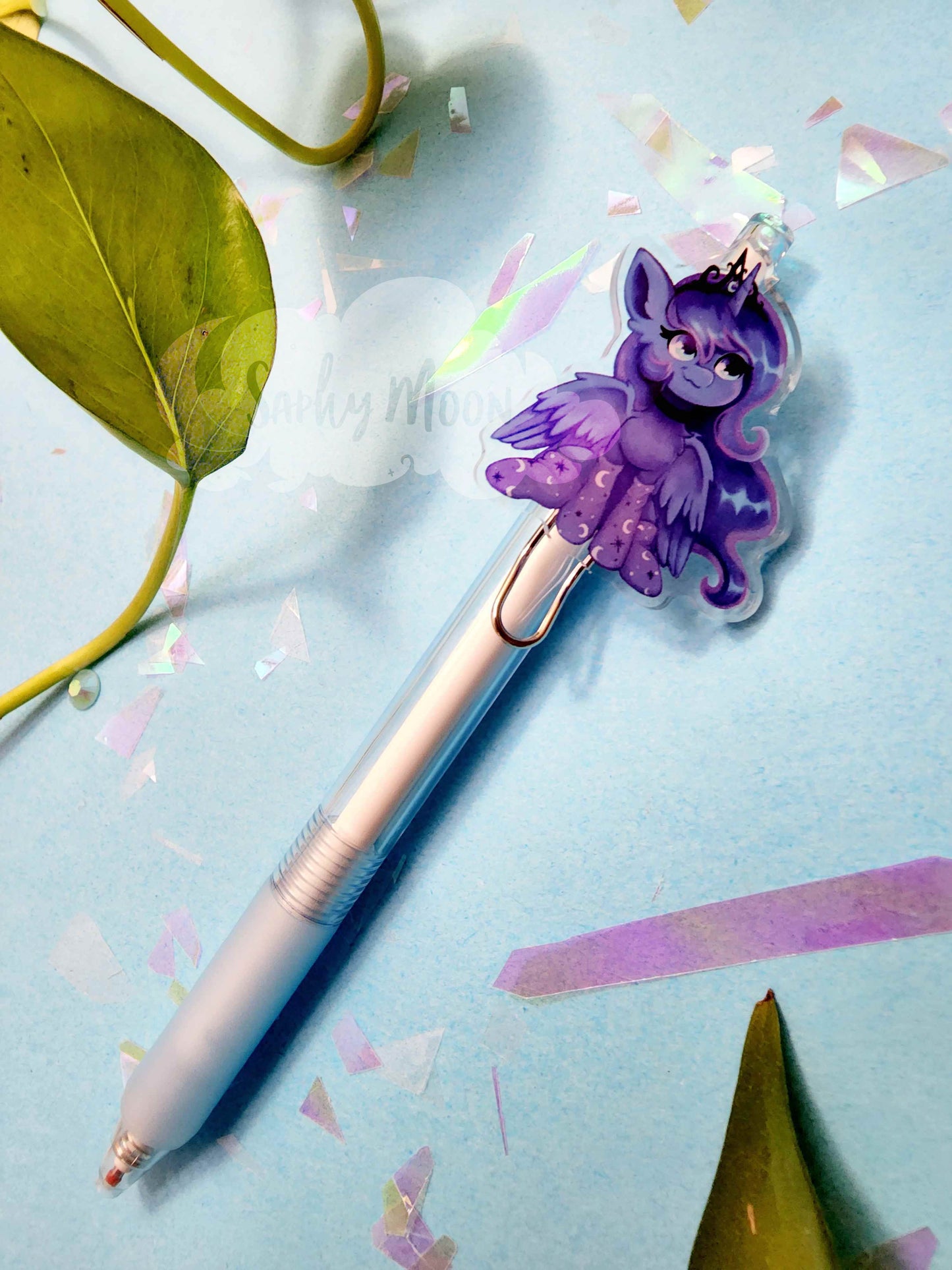 Pen with a purple character sticker on a light blue background with confetti