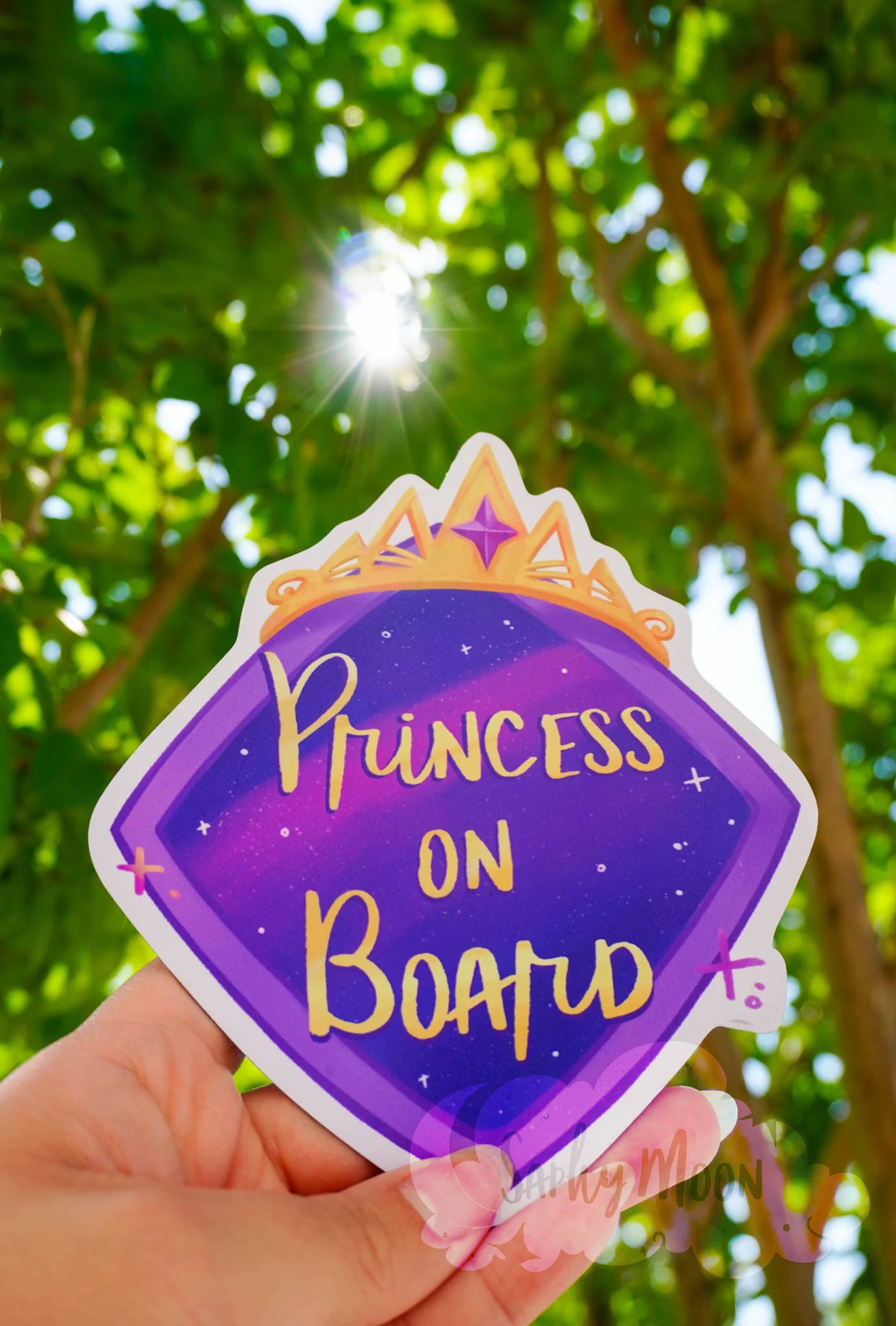 Magnet with 'Princess on Board' text held in front of a green leafy background