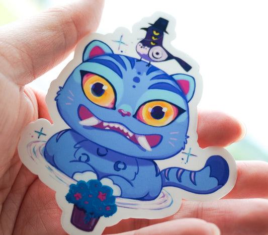 Colorful sticker of a blue tiger with large eyes held in a hand.