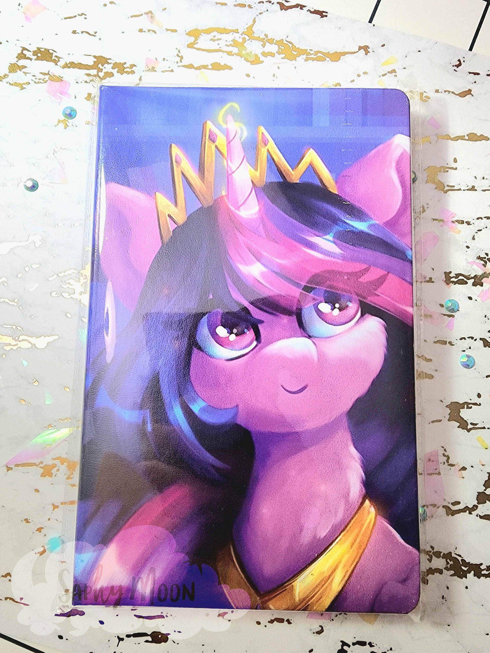 Card with a stylized purple unicorn wearing a crown on a glittery surface